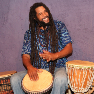 Artist Baba Ras D playing a djembe.